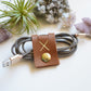 Handmade Cognac leather cord keeper wrapped around a braided charging cable, large snap closure cable organizer for USB cords, power cables, device chargers and clutter-free storage by Keyaiira
