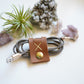 Personalized brown leather cable holder with custom initial, handmade cord wrap styled with natural decor for charger organization, home office storage and minimalist desk accessories by Keyaiira
