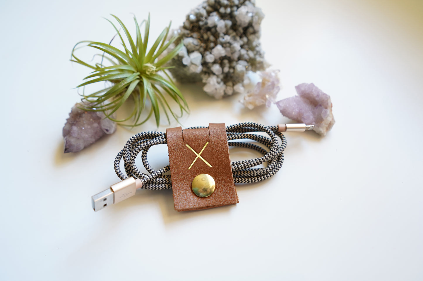 Personalized brown leather cable holder with custom initial, handmade cord wrap styled with natural decor for charger organization, home office storage and minimalist desk accessories by Keyaiira

