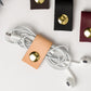 Veg Tan genuine leather earbud organizer with brass snap closure, artisan-made Keyaiira cord wrap for wired headphones, charging cables, small electronics and tangle-free travel storage
