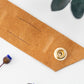 Genuine Cognac leather cable management strap with brass snap hardware, handcrafted by Keyaiira for bulky charger cords, power cables, computer wires and home office organization
