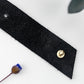 Black genuine leather cable organizer with brass hardware, reusable cord keeper and minimalist leather cable tie for chargers, headphones, computer cords and office tech organization by Keyaiira
