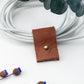 Rich brown full-grain leather charger keeper fitted around a coiled white cable, thoughtfully designed by Keyaiira for compact cord control, device storage and clutter-free organization
