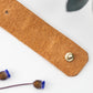 Nicotine full-grain leather cable management strap with brass hardware, hand-finished by Keyaiira for phone charger cords, USB cables, electronics accessories and streamlined desk storage
