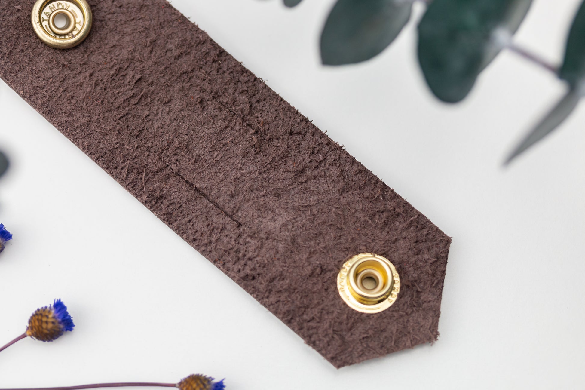 Dark brown genuine leather cable tie with double brass hardware, minimalist handmade cord holder for chargers, electronics cables, computer accessories and home office organization by Keyaiira
