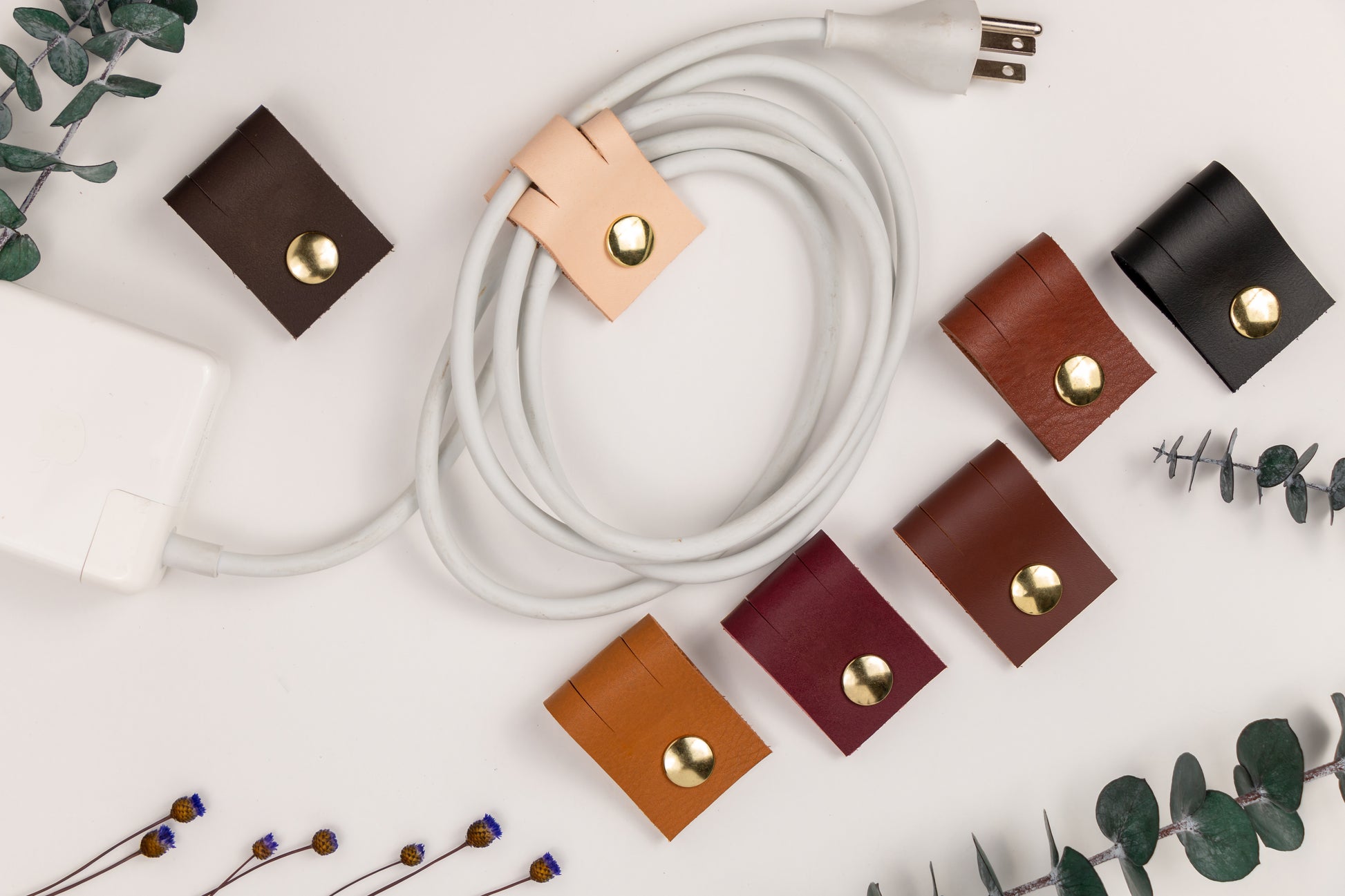Black genuine leather cord keeper with double brass snap closures, minimalist cable management strap for charging cords, USB cables, headphones and home office electronics by Keyaiira
