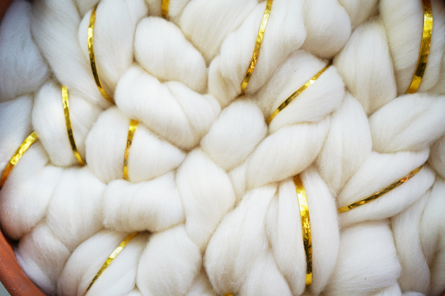 Organic glam home decor piece featuring raw white wool and hand-thrown clay. Woven gold metal accents catch the light, adding a touch of sophisticated shimmer to this rustic glam wall sculpture.