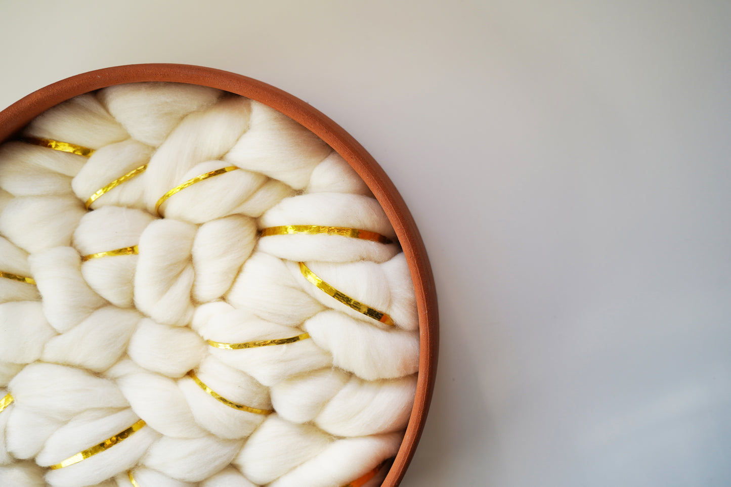 A luxurious take on rustic home design. This terracotta and wool vessel integrates delicate gold metallic strands to create a "rustic glam" aesthetic, bridging the gap between raw nature and refined elegance.