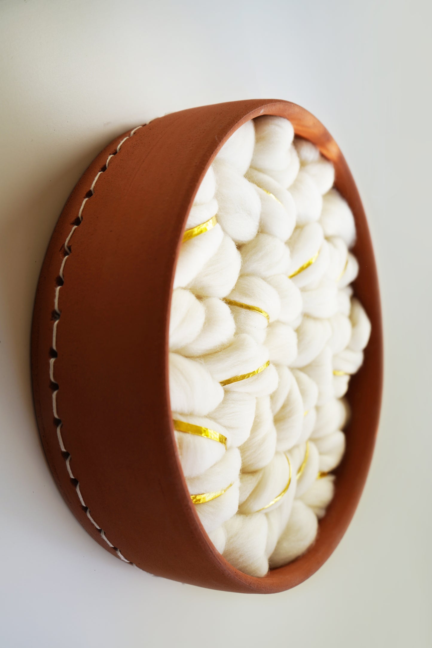Side angle of the "Rey" wall sculpture showing the 3-inch depth of the hand-thrown terracotta frame. Demonstrates the high-relief dimension where the wool fibers bow outward from the ceramic vessel.