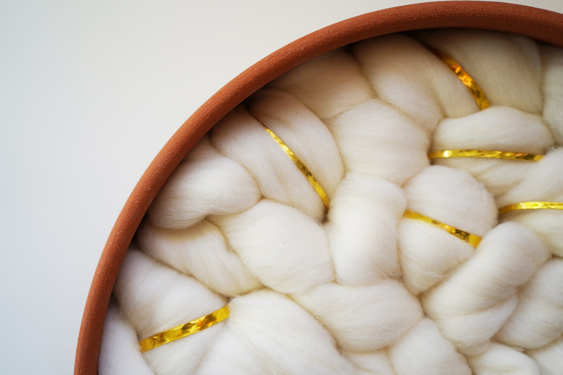 Sustainable bohemian wall decor hanging on a white wall. The warm earth tones of the terracotta and the creamy white wool add a calming, organic element to a living room or nursery.