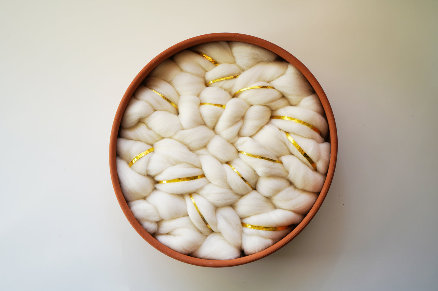Round terracotta wall hanging with white wool interior. Hand-thrown ceramic art made in Sonoma, CA. Minimalist earth-tone decor measuring 12 inches in diameter.