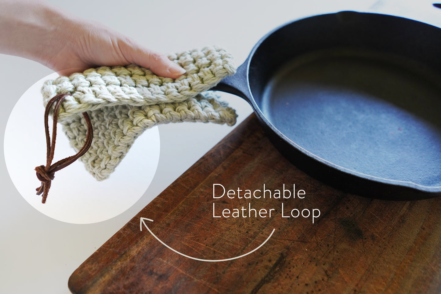 Detachable leather hanging strings by Keyaiira attached to a crocheted knit potholder and shown near cookware handcrafted leather hanging strings for organizing kitchen textiles.