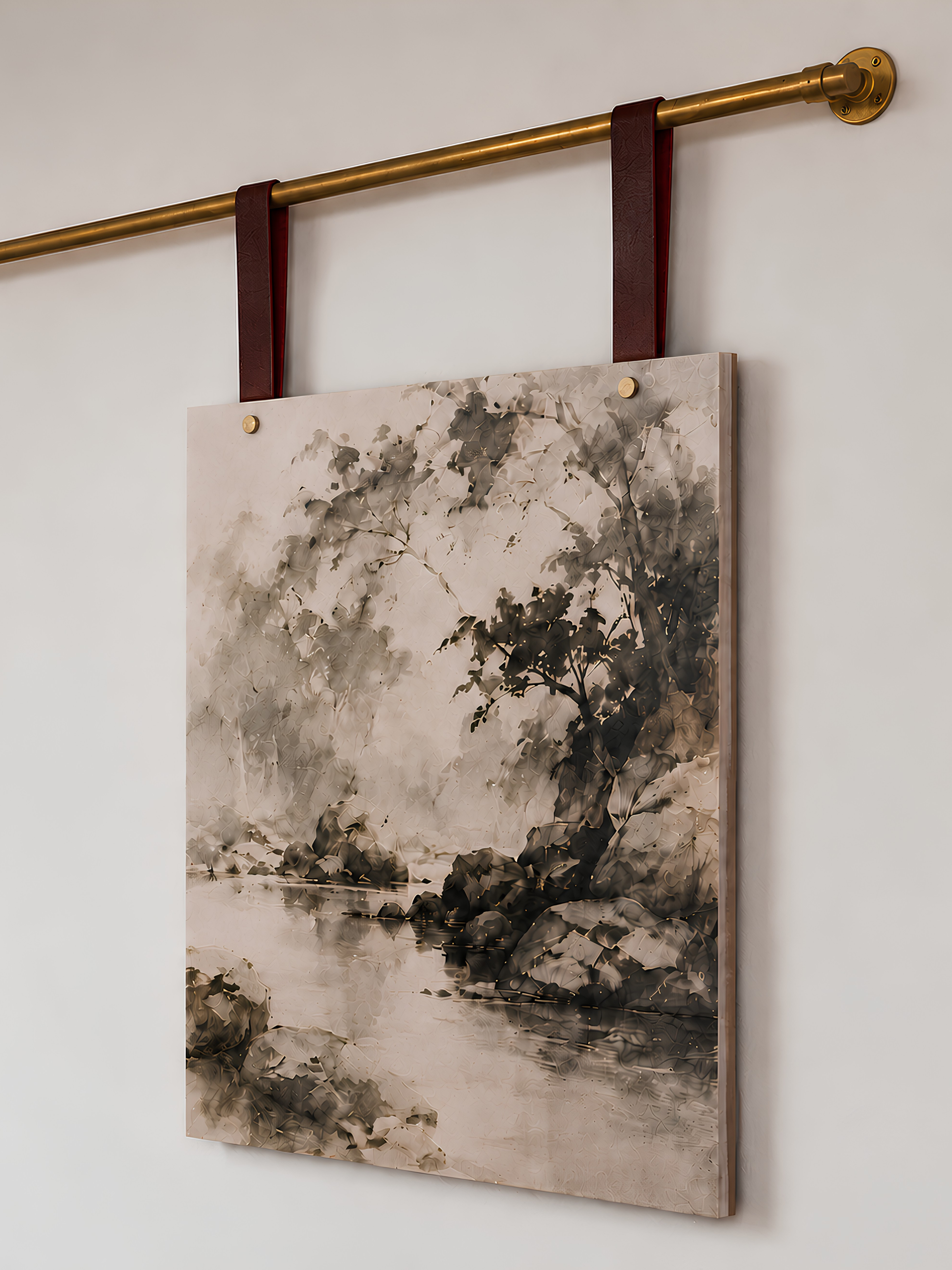 A vertical canvas wall art print featuring an ink-wash style landscape painting of trees and water, hanging from a brass rod with dark red leather straps against a plain white wall.