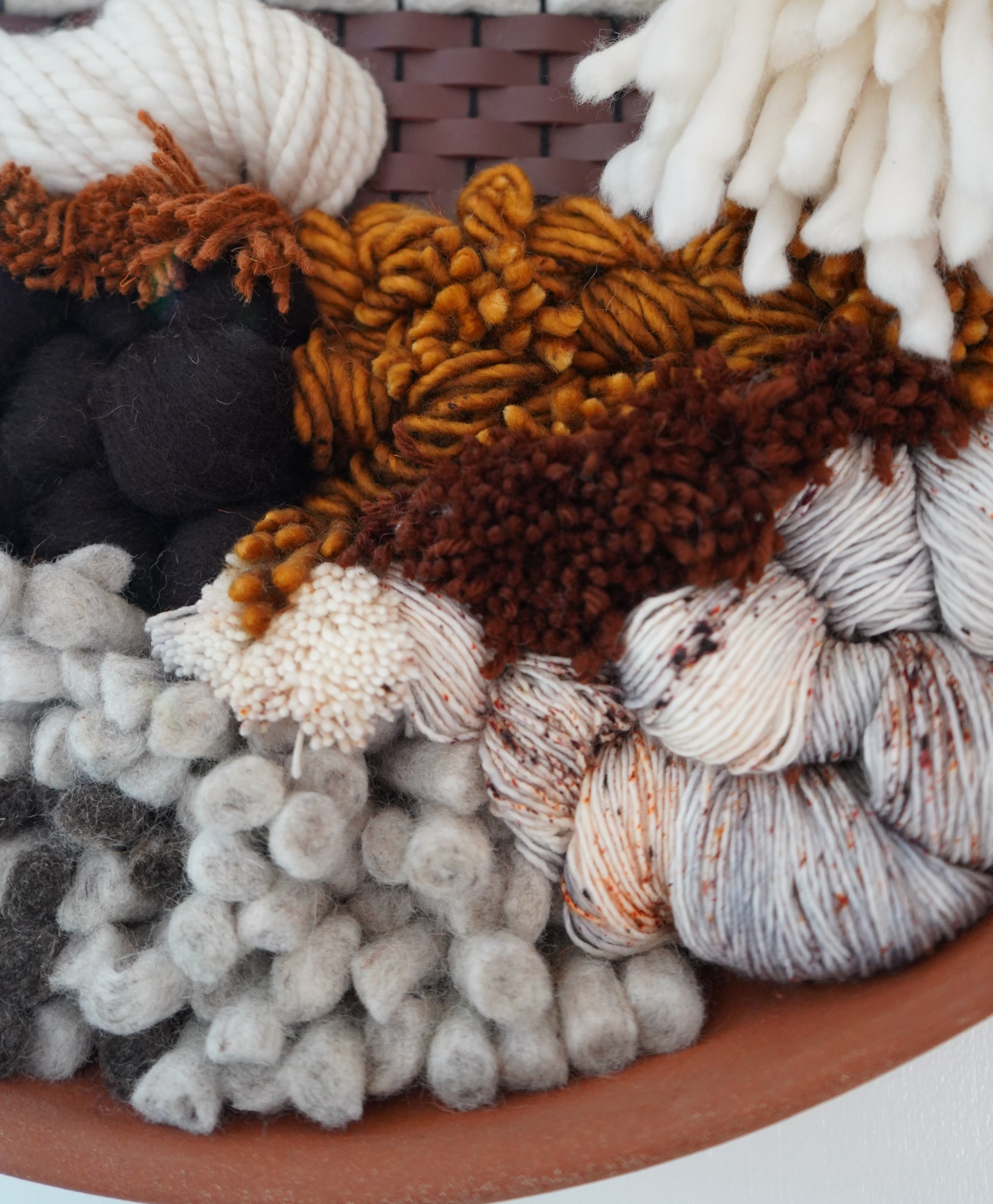 Detail of speckeld yarns woven in with stiff felted wool spears and tacktile maroon wool and leather