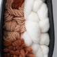 Close view of the woven interior showing textured Targhee wool, thick Rambouillet roving, and hand spun brown yarn inside a hand formed black clay frame. Detailed look at the natural fibers and organic texture by Keyaiira