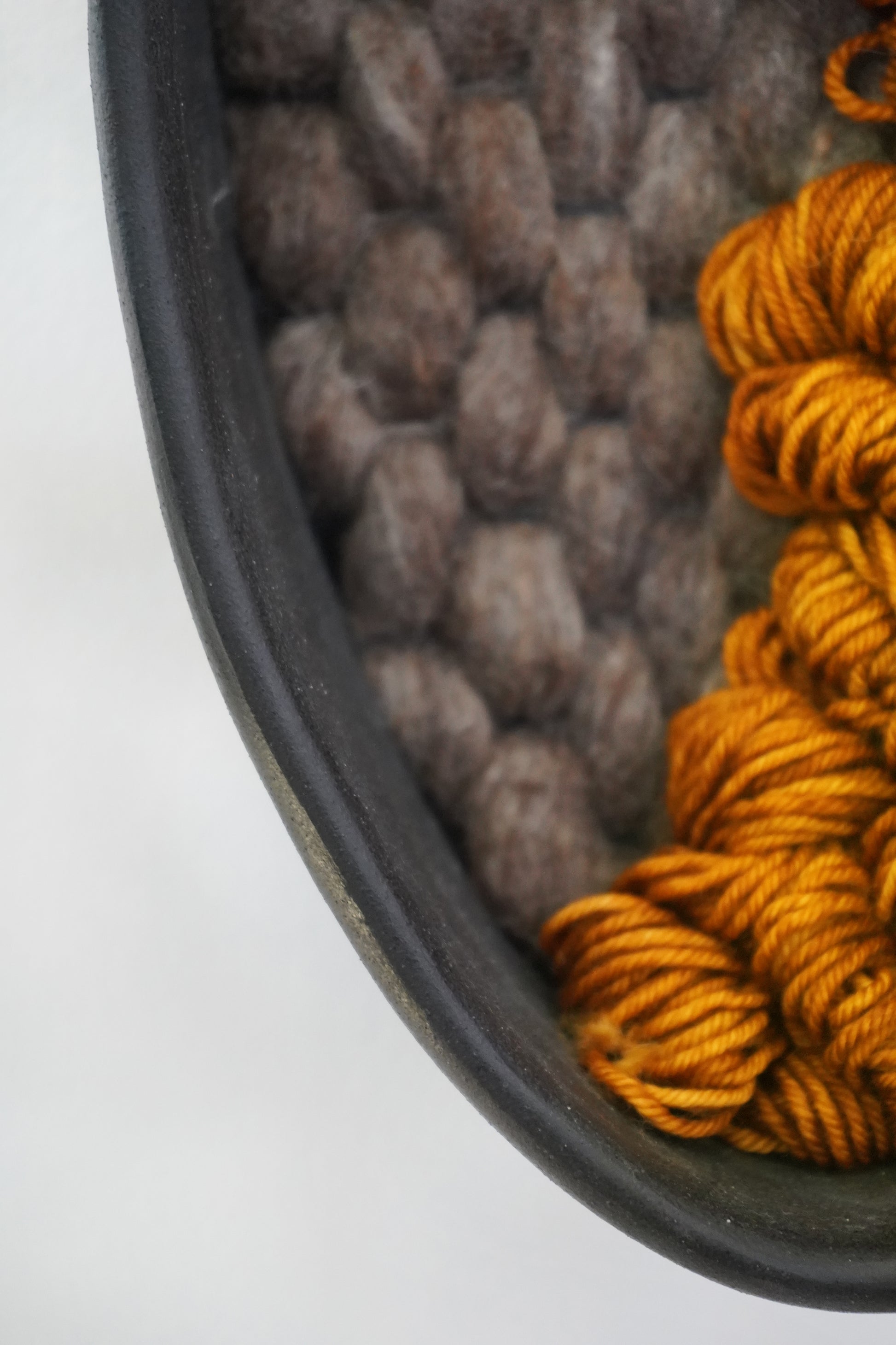 Detail close-up showing textural ochre wool loops against felted gray wool, highlighting fiber variation.