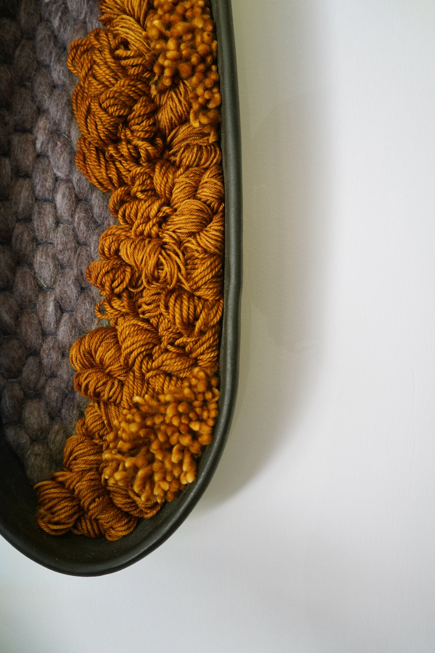 Artistic close up showing bottom of hand-formed clay and wool loops. Intricate fiber art craftsmanship and textile details in a unique one of a kind mixed media wall sculpture.