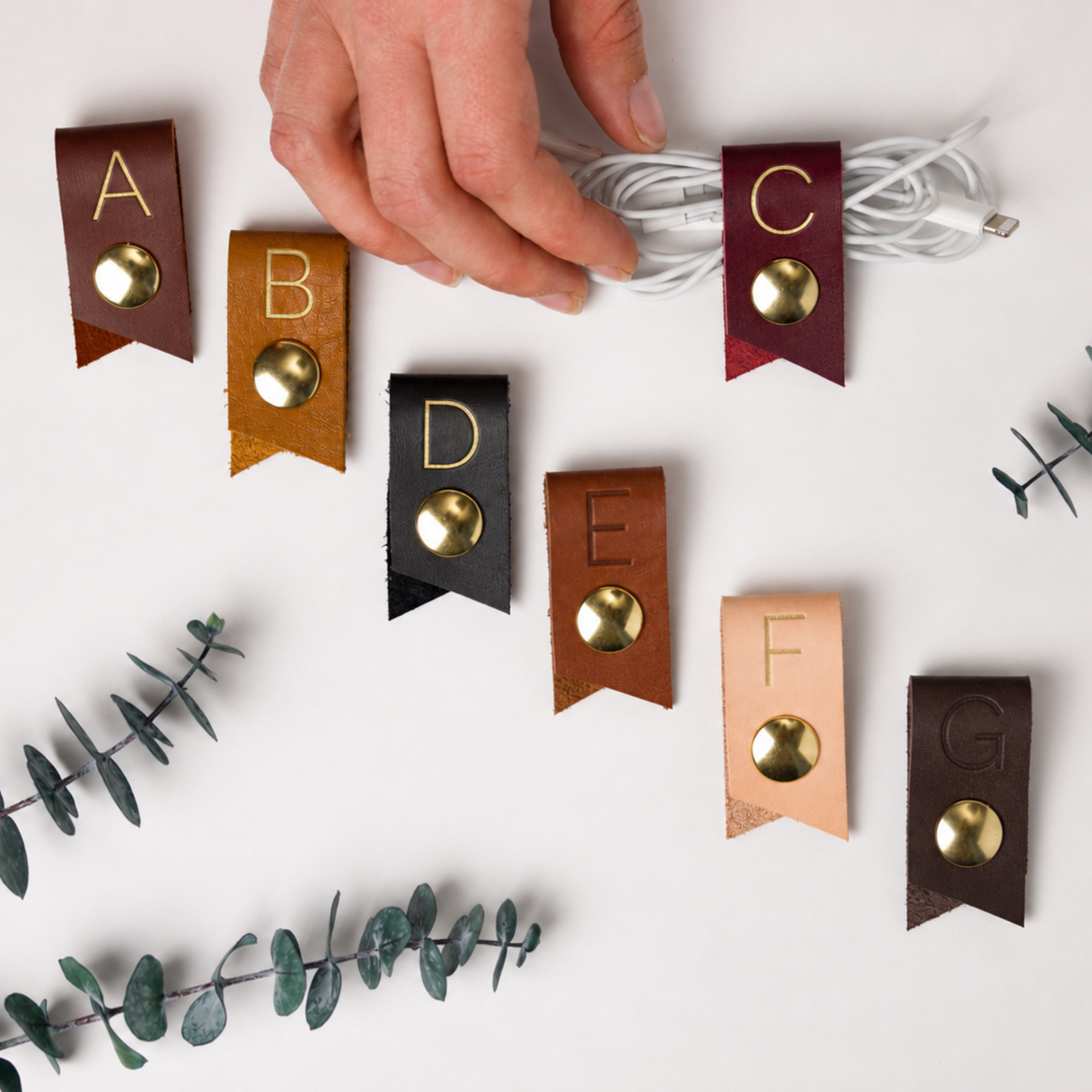 Custom initial leather cord keepers in assorted Keyaiira colors, handmade cable organizers for earbuds, phone chargers, USB cords and small everyday tech accessories
