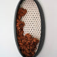 Sustainable wall decor made from ethically sourced materials. Matte black ceramic vessel filled with hand-dyed rust wool yarn and ivory hand-felted fibers. Sophisticated California design.