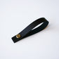 Black leather hanging loop with brass rivet on white background — handcrafted removable leather loop by Keyaiira.