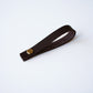 Chocolate leather hanging loop with brass rivet on white background  handcrafted detachable leather loop by Keyaiira.