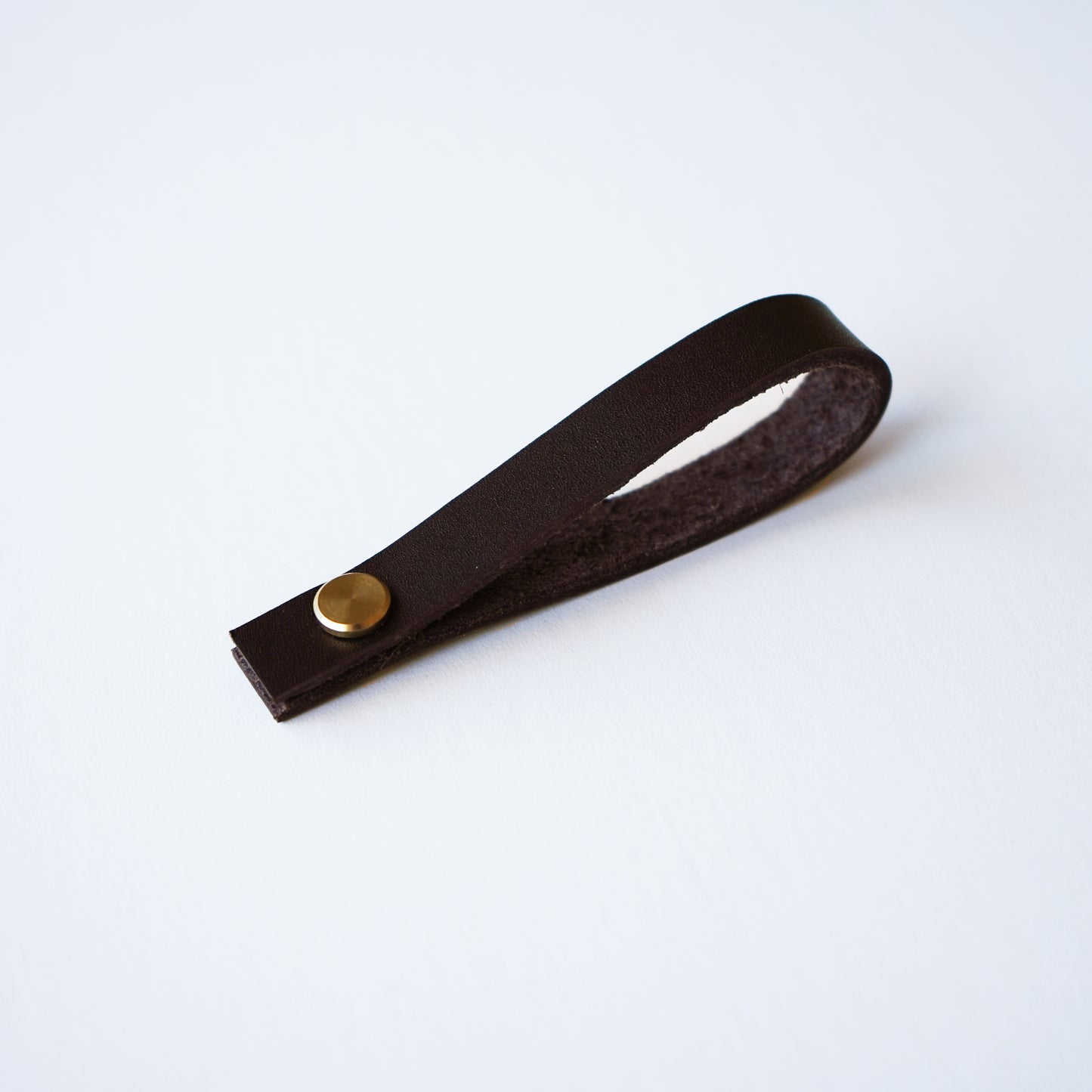 Chocolate leather hanging loop with brass rivet on white background  handcrafted detachable leather loop by Keyaiira.