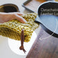 Detachable leather hanging strings by Keyaiira holding a green crocheted knit potholder over a counter edge — handcrafted leather hanging strings for functional kitchen storage.