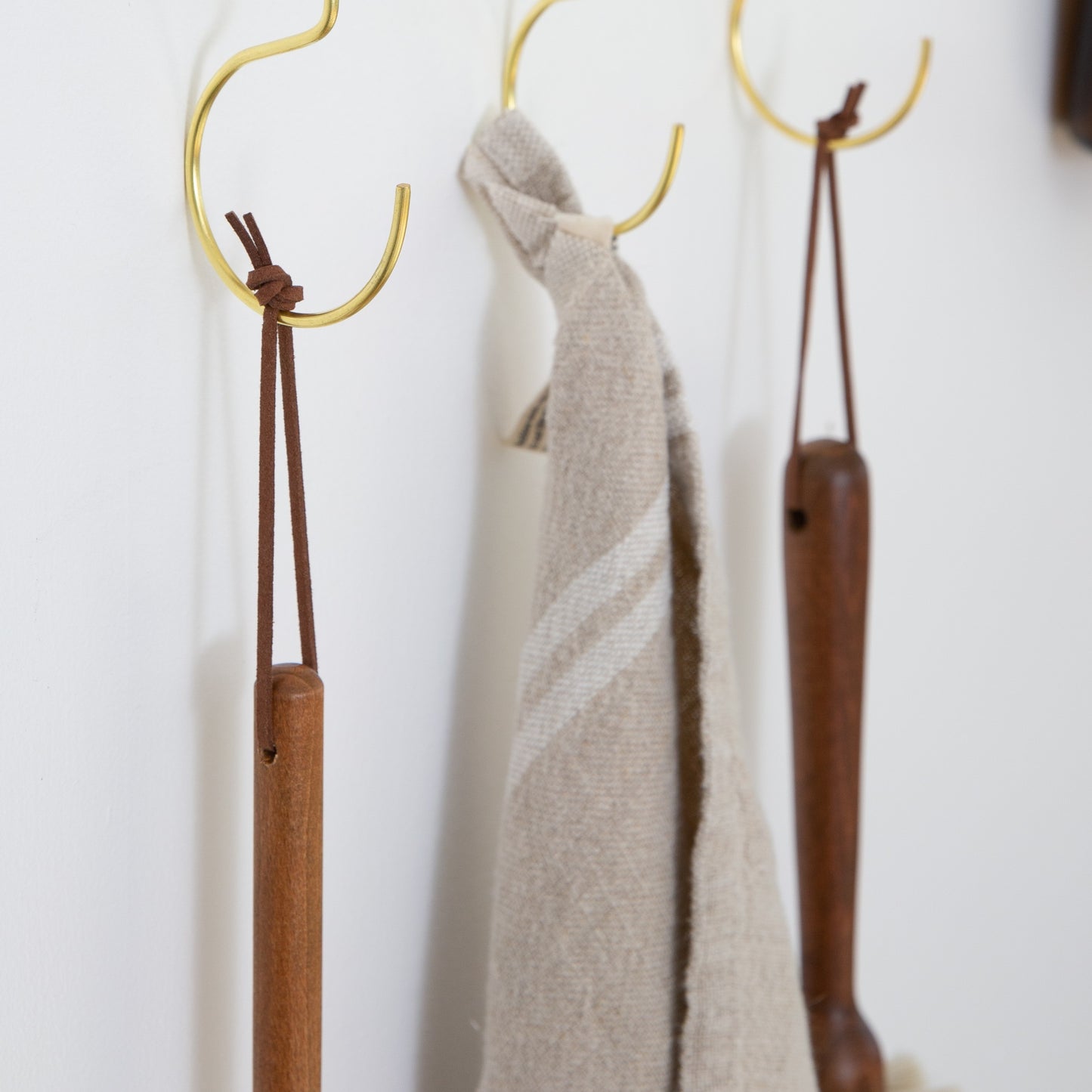 Detachable leather hanging strings by Keyaiira used with wall hooks to hang kitchen towels and wooden utensils — handcrafted leather hanging strings for organized kitchen storage.