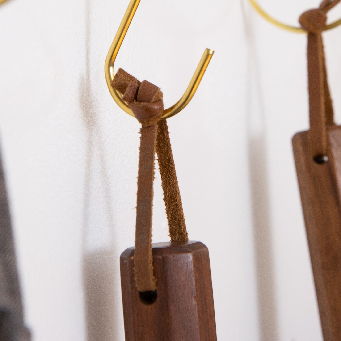 Close-up of detachable leather hanging strings by Keyaiira knotted onto a brass wall hook — handmade leather hanging strings used for hanging kitchen tools, utensils, and home accessories.