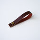 Wine colored leather hanging loop with brass hardware on white background minimalist leather hanging loop by Keyaiira.