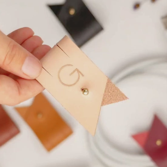 Keyaiira large leather cable holder demonstration featuring a custom G initial and Stud & Post hardware for securing charging cords, device cables and tech accessories
