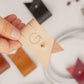 Keyaiira large leather cable holder demonstration featuring a custom G initial and Stud & Post hardware for securing charging cords, device cables and tech accessories
