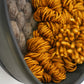 Close side view of handwoven wool artwork showing rich rusted orange texture inside black clay frame.